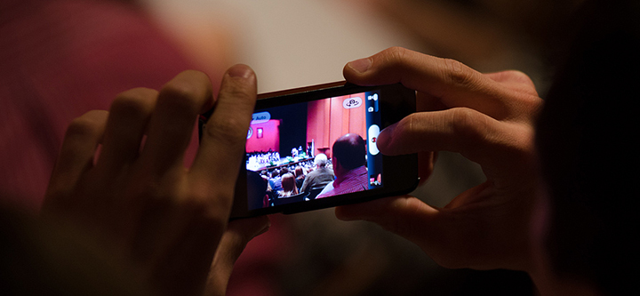 A parent uses a phone to capture the 2013 Commencement.
