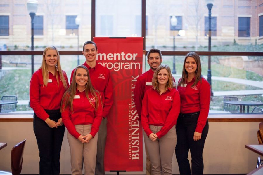 A group of students standing next to mentor program sign
