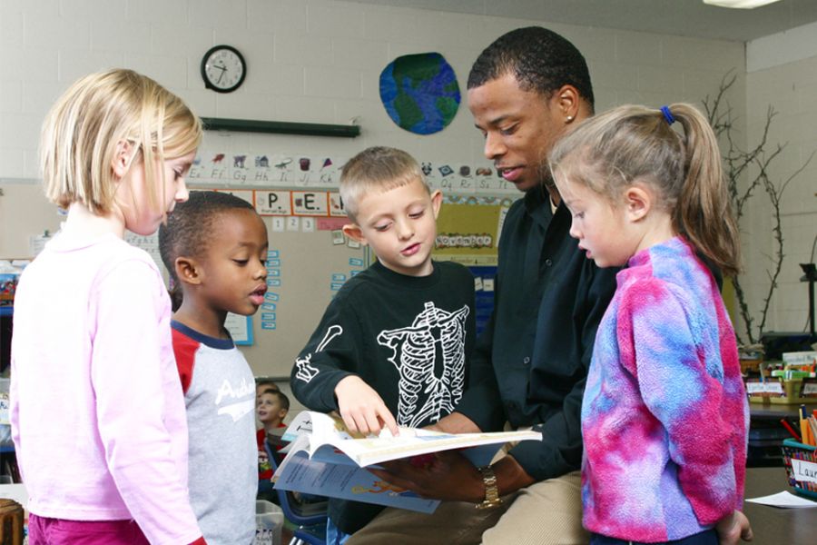 An Illinois State education major collaborates on a literacy lesson with several students.