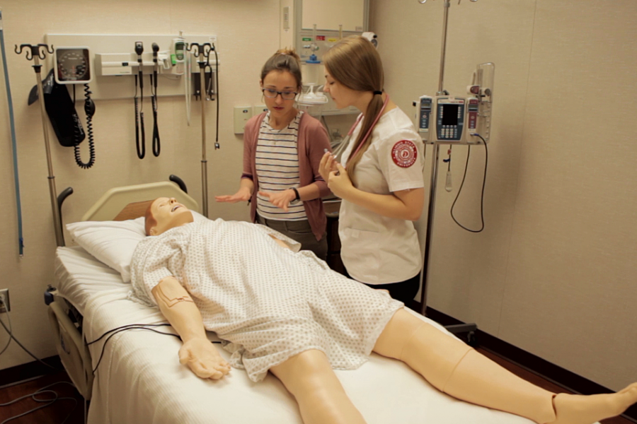 Spencer Simpson leans over a patient simulator