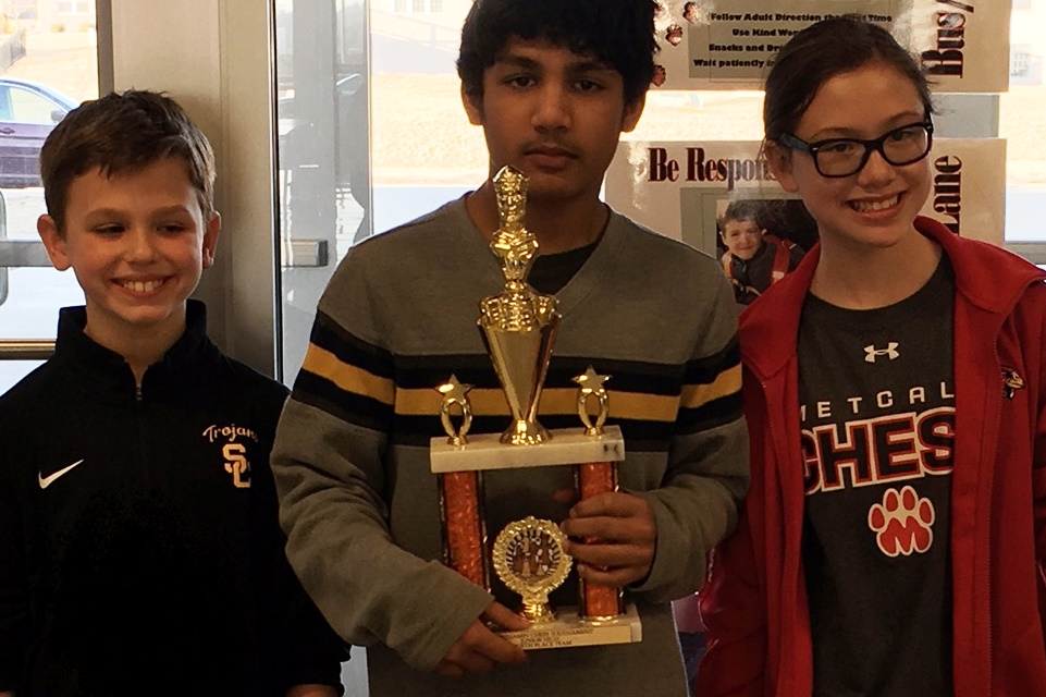 students pose with their fourth place Junior High division chess trophy.
