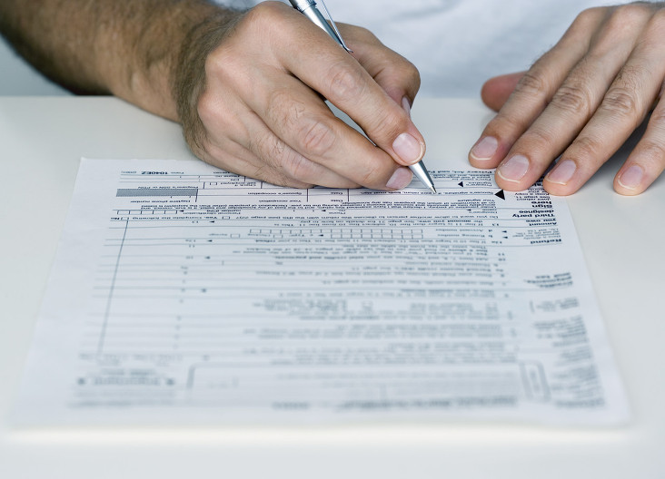 Man Filling out Tax Form --- Image by © Royalty-Free/Corbis
