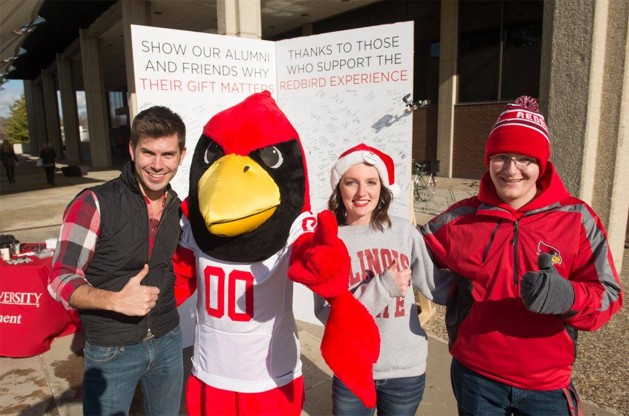 Reggie and students stand in front of a giant thank you card during Giving Tuesday 2015.