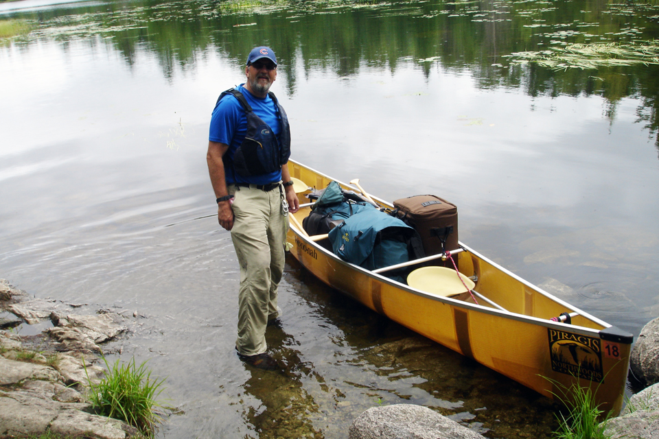 man standing next to canoe