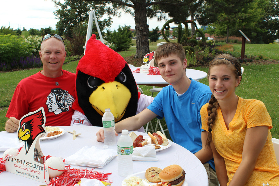 Family of three sitting at table with Reggie Redbird