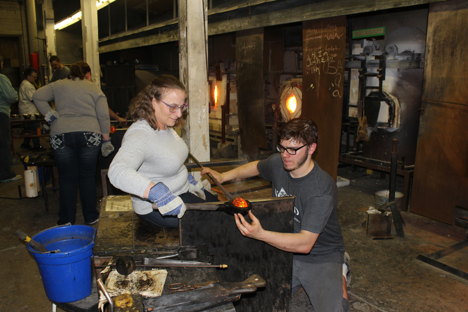 Tyler Wolf, recipient of the Pilchuck School Partnership Scholarship, teaches alumni how to work with glass at a spring alumni event. Participants supported the scholarship for Tyler to travel to the Pilchuck School.