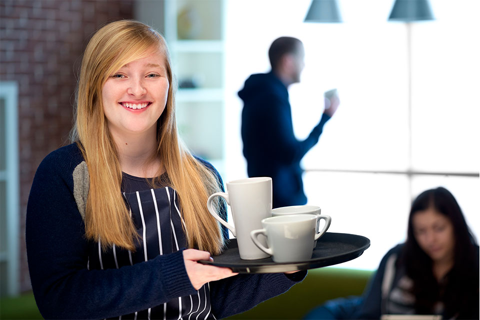 Girl holding tray with coffee mugs on it.