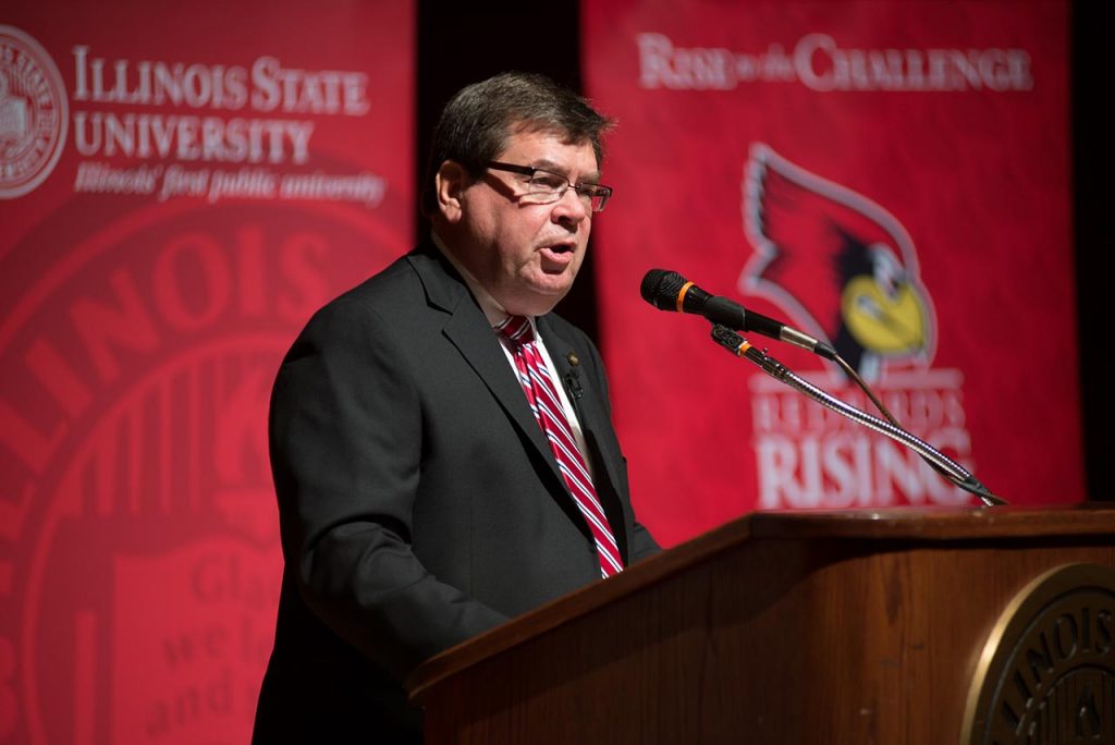 Larry Dietz at a wood podium with banners for Illinois State University in the background.