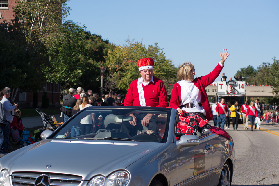 two people waving from car in parade