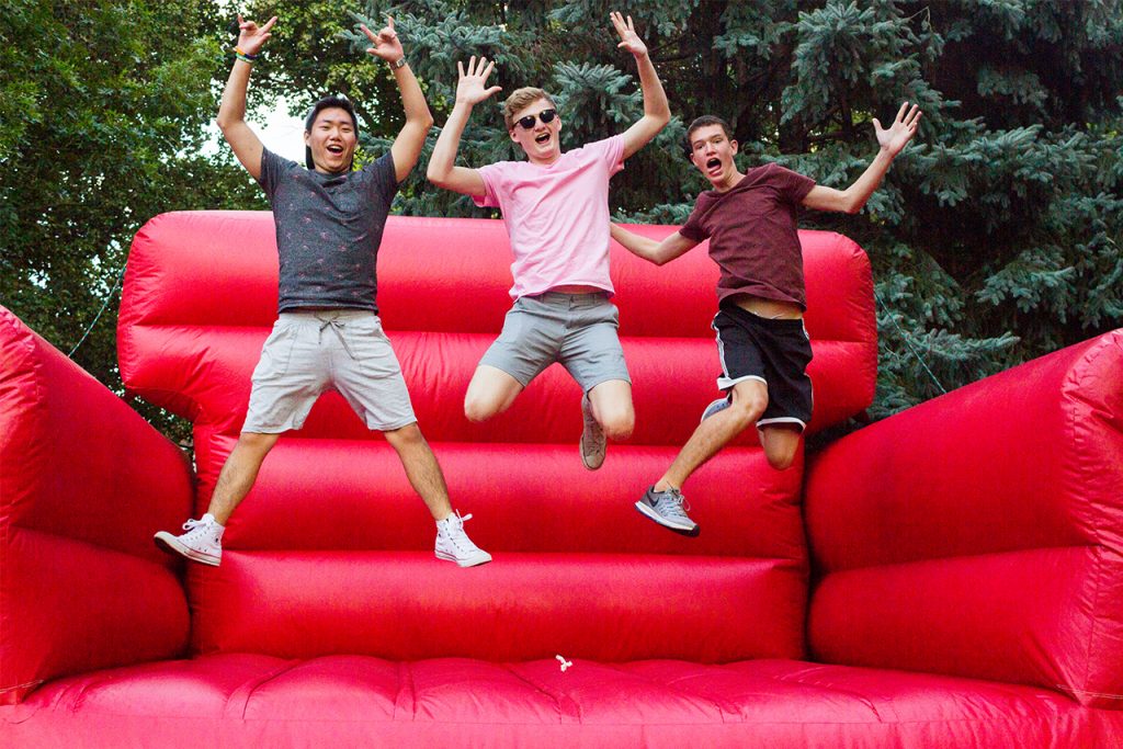 Illinois State students jump on inflatable red chair on the quad
