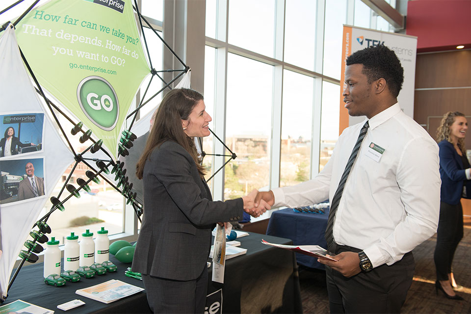 employers graciously greets a Redbird candidate at a career fair