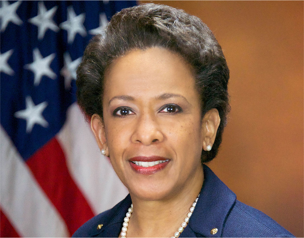 Former U.S. Attorney General Loretta E. Lynch standing in front of an American flag.