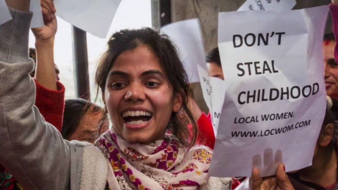 woman shouting and holding a sign that denounces child labor