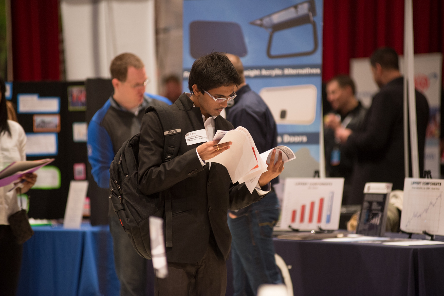 A male student looking through several flyers and pieces of paper at a Career Fair.