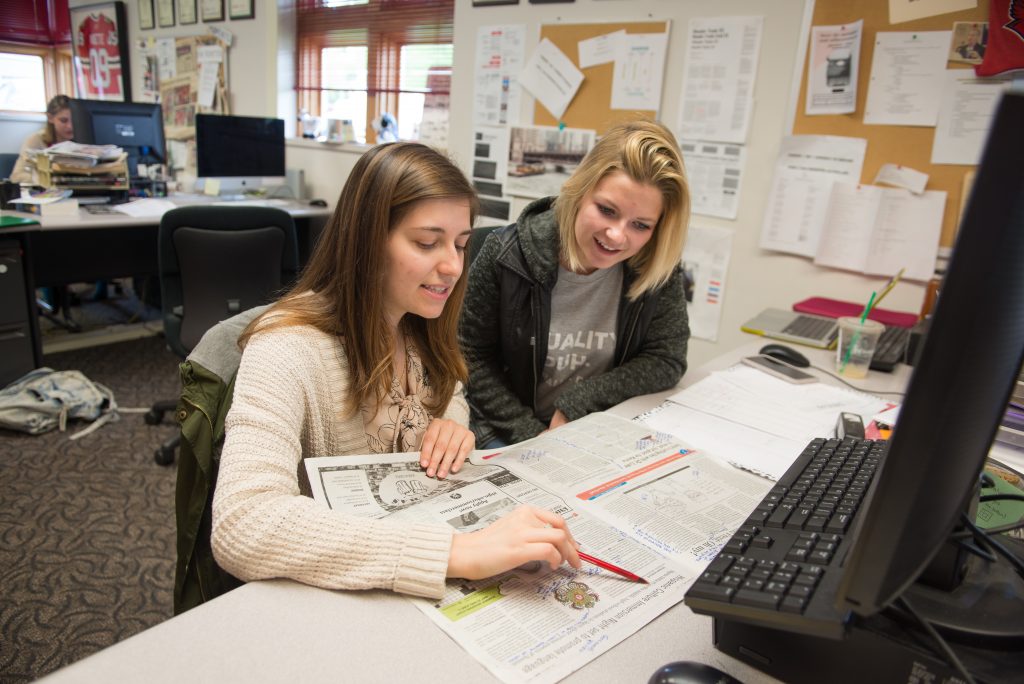 Two students working on a page layout for the Vidette student newspaper.