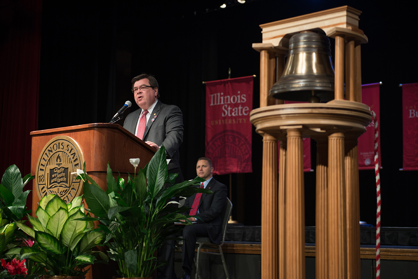 President Larry Dietz at a podium with the replica of the Founders Bell beside him.