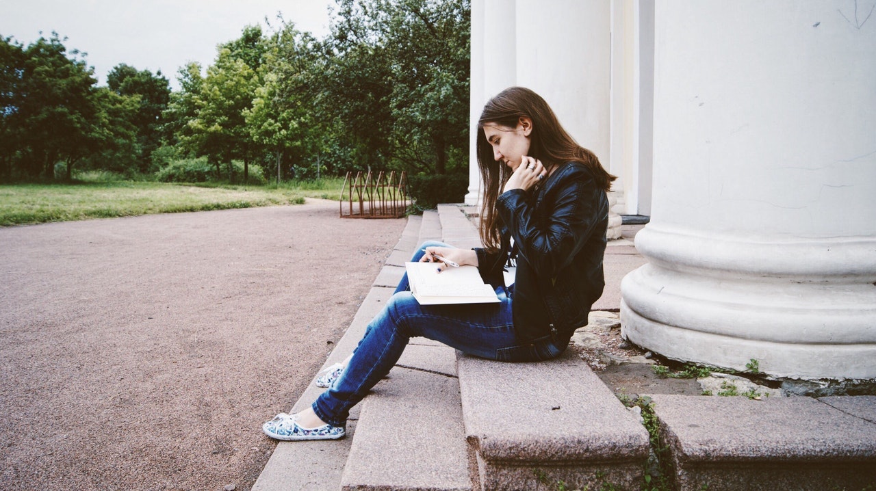female college student reading on steps