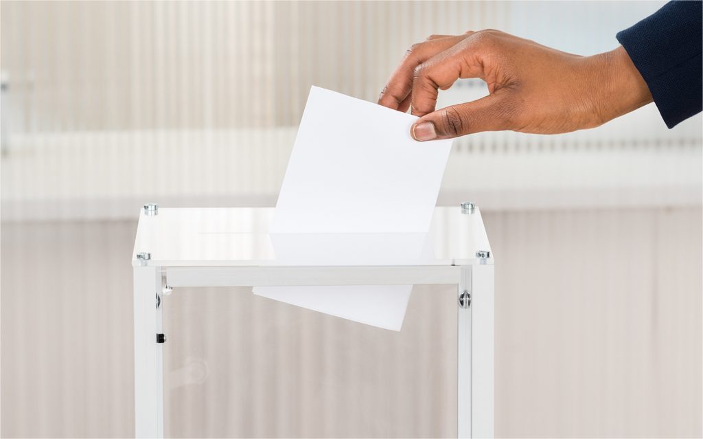 hand casting a ballot into a ballot box