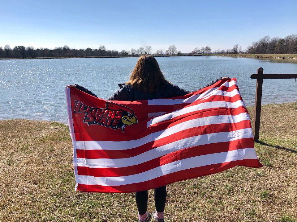 Student with ISU flag overlooking a lake