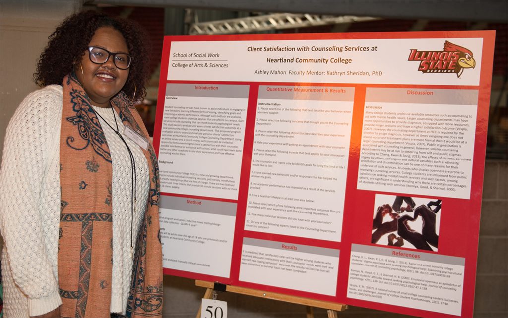woman standing in front of a poster of her research on counseling services