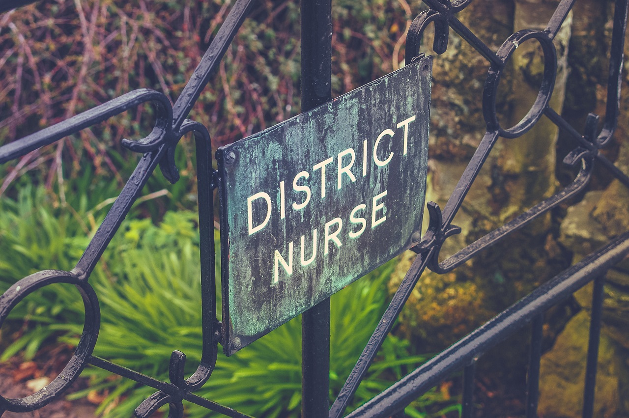VIntage Style Photo Of A District Nurse Sign On A Garden Gate