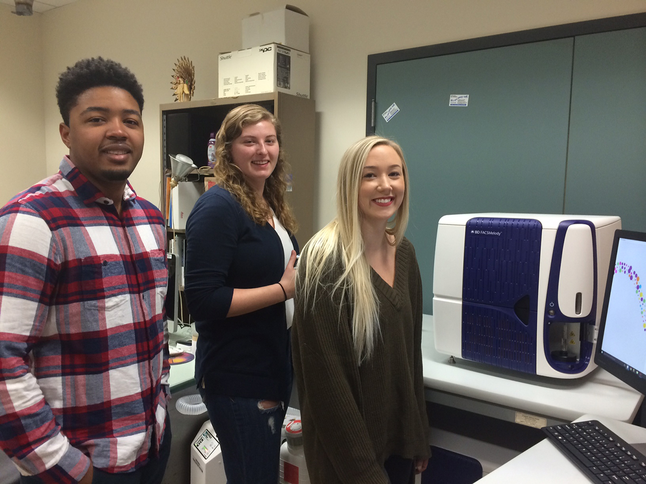 Three students standing in front of the new machine