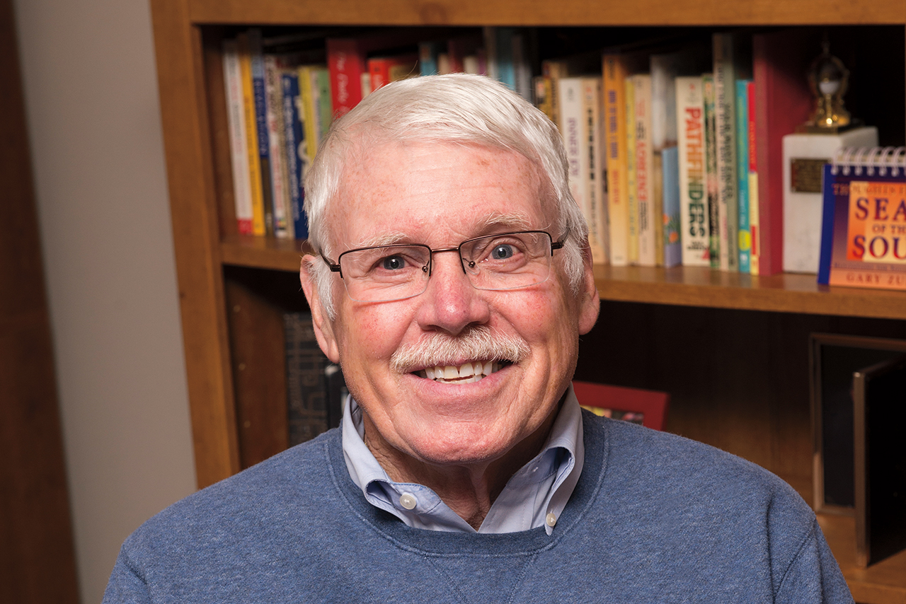 Psychology Professor Emeritus Doug Lamb in front of shelves of books