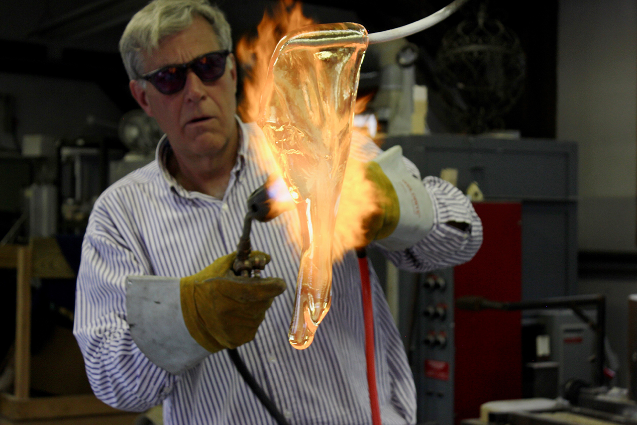 Image of alumnus Robert DuGrenier working with hot glass