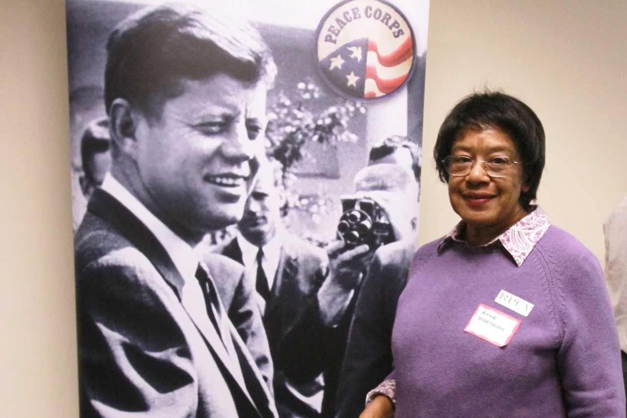 Anne Wortham next to Peace Corps poster of Kennedy