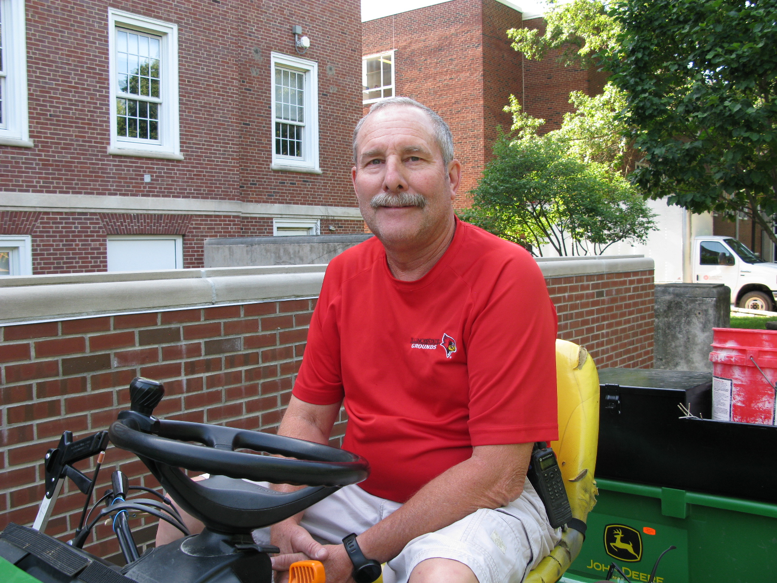Tom Cotton, seated on his John Deere tractor on a sidewalk outside Hovey Hall