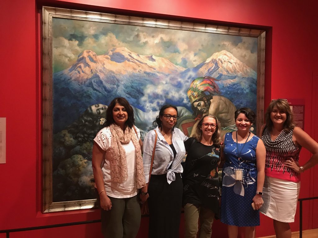 Five women standing in front of a painting