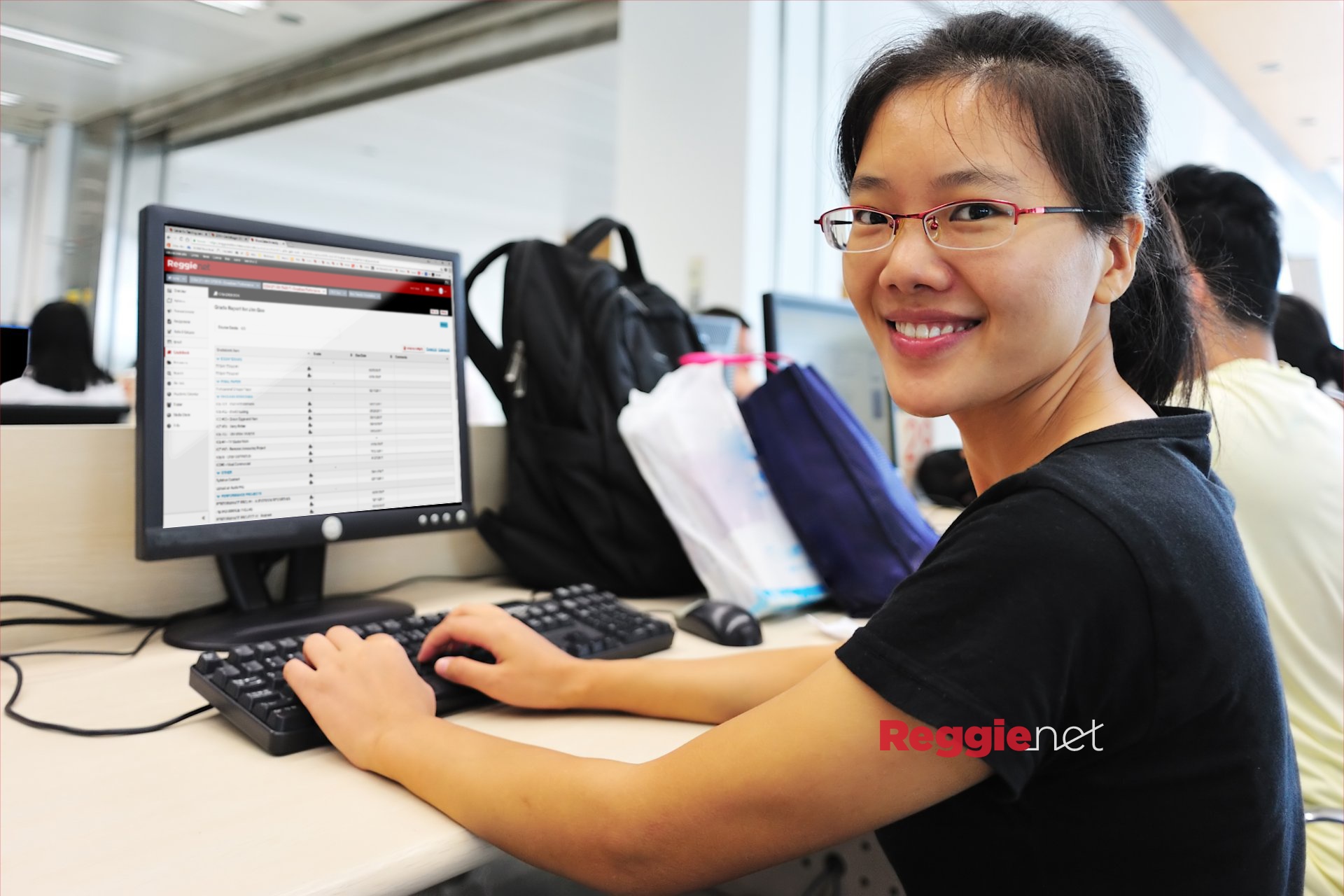 Student smiling, ReggieNet on computer screen