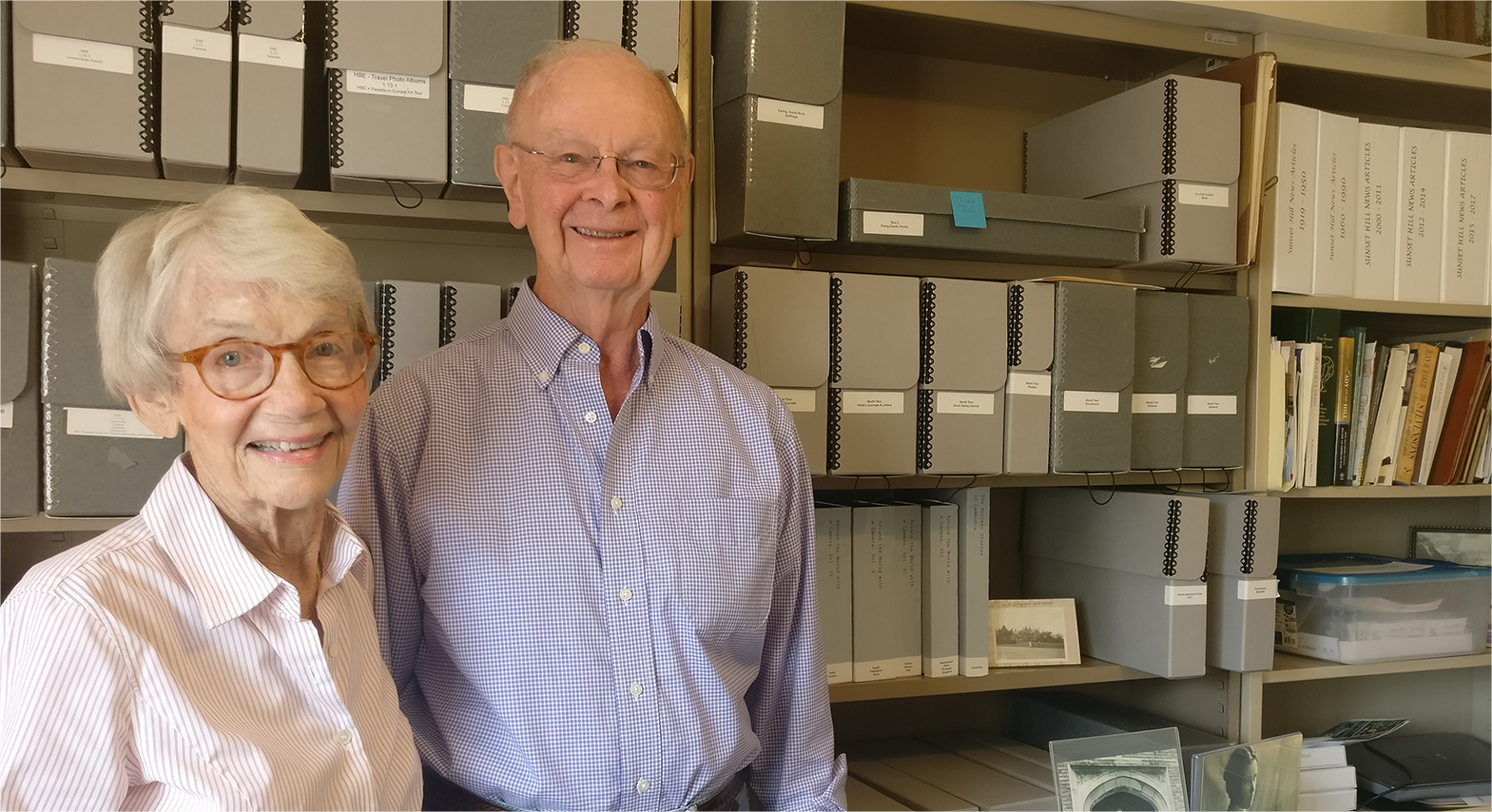 A man and woman standing in front of shelves of archive boxes
