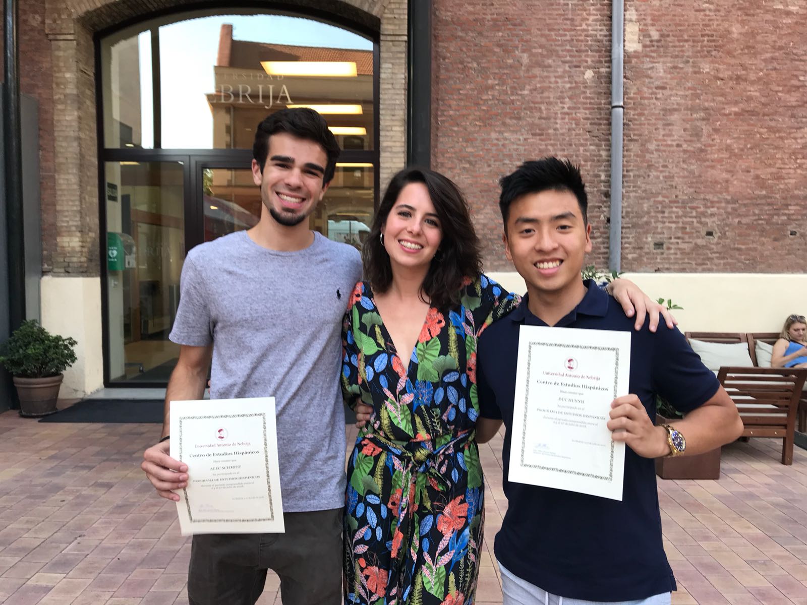 Three people standing outside, two holding up pieces of paper