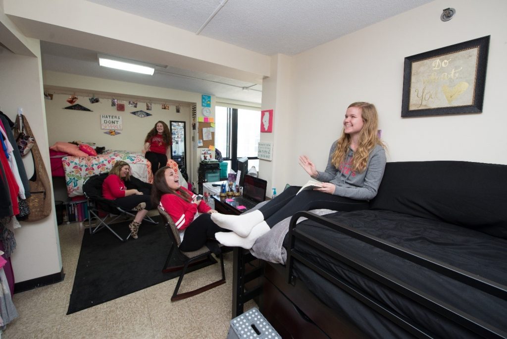 women laughing and sitting on furniture in a residence hall room