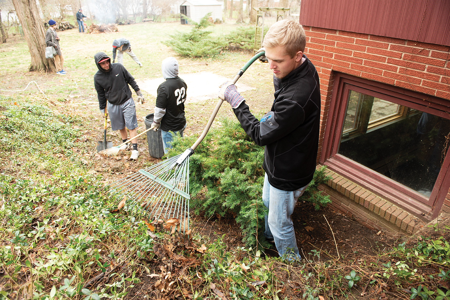 Last April, more than 170 students spread out across Bloomington-Normal to lend a hand to residents and community organizations for the 10th annual Bring It Back to Normal. Students raking and do outside chores at a home.