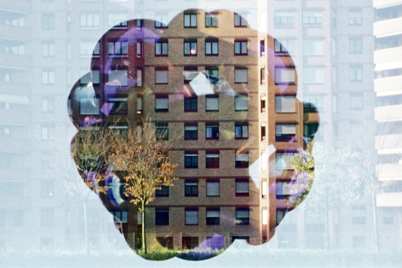 Photo of the artwork. Looks like you are looking at an apartment high rise from a window that has been covered in steam, but that someone has taken a finger and rubbed the glass in one spot to see out of. Basim Magdy, The Dent, 2014. Super 16mm film transferred to full HD video, 19:02 minutes. Commissioned by the Abraaj Group Art prize 2014. Courtesy of the artist.
