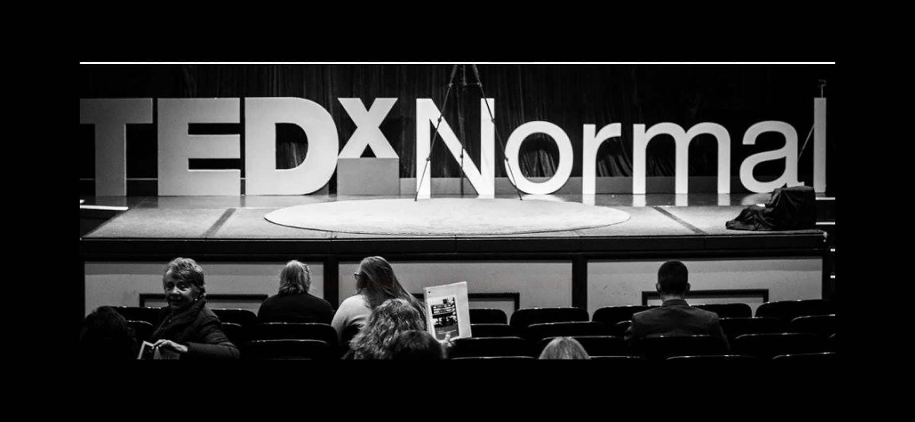 Large letters on a stage spelling out TEDxNormal