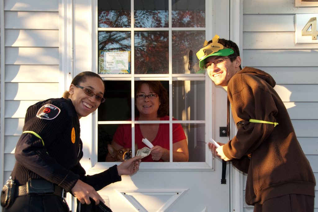 Two students stand at a door to collect a donation from a resident