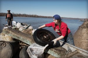 Illinois State student Kaitlyn Remian loads a discarded tire onto a boat on the Mississippi River as part of a cleanup during an Alternative Breaks trip to Grafton, Illinois.