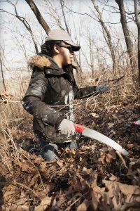 Asiah Claiborne, a graduate trip advisor and veteran of seven Alt Breaks trips, clears honeysuckle bush from the nearby wooded bluffs.