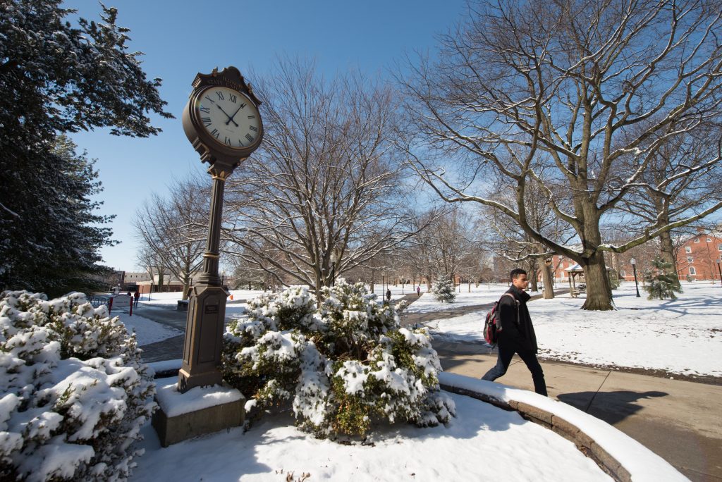 A student walks by a clock on Illinois State's Quad.