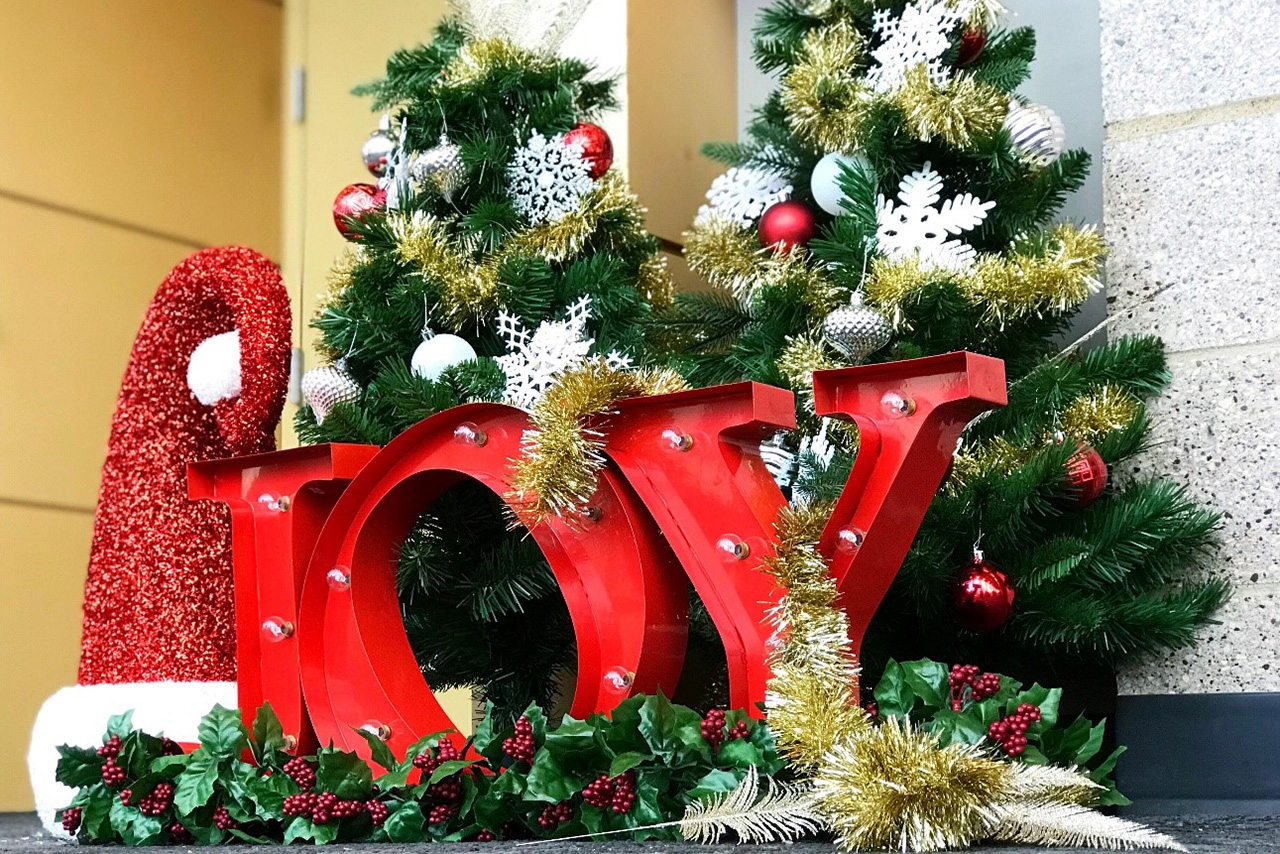 Holiday decorations: trees, Santa hat, and the word Joy in the CPA Loby