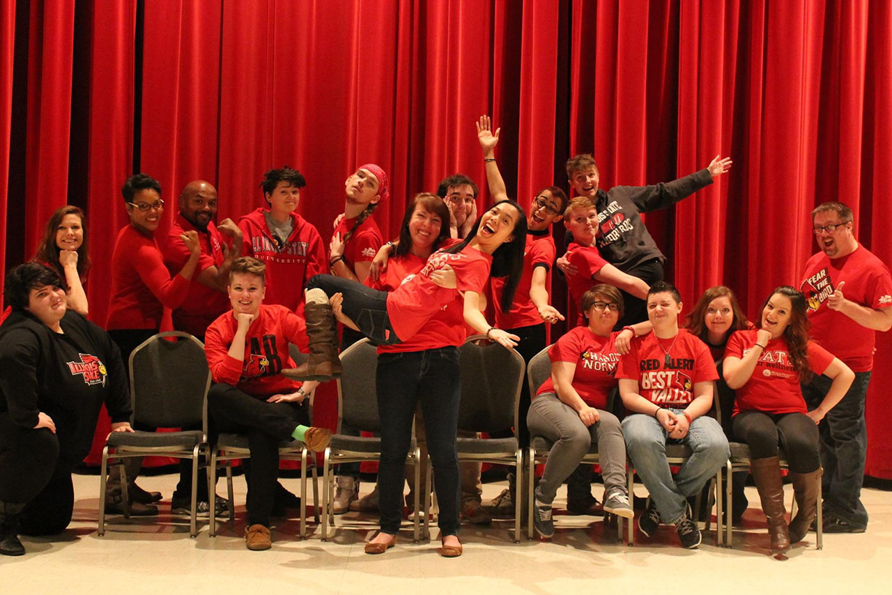 conference staff and students pose together in front of red background