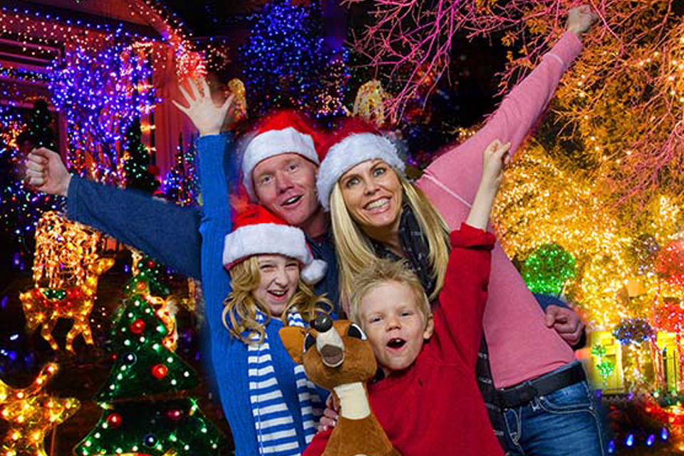 Family cheering in front of Christmas lights
