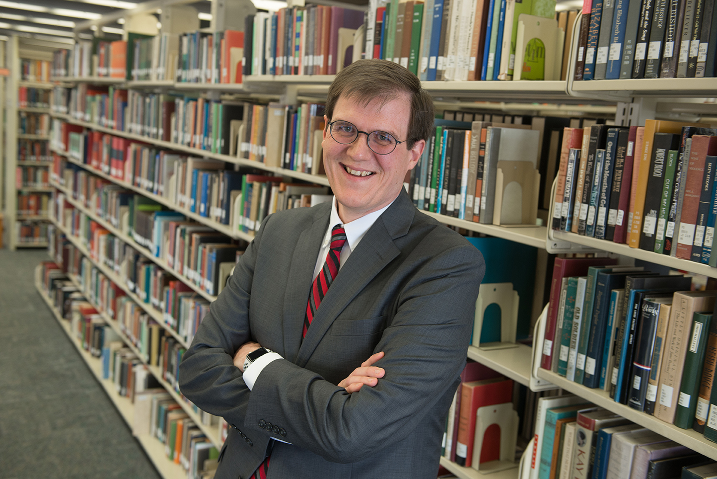 image of Paul Unsbee standing in front of the stacks at Milner Library