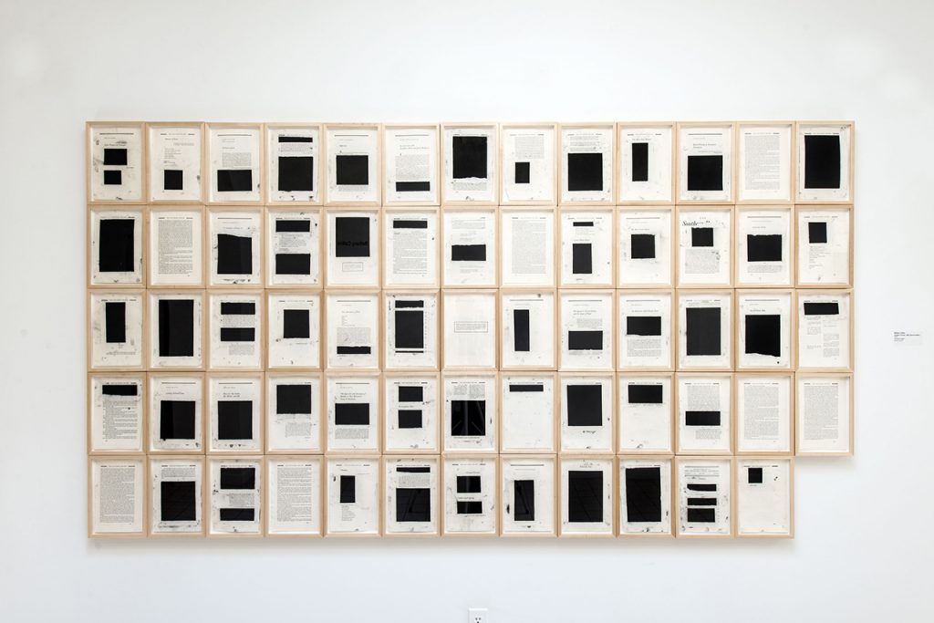 Artwork by Bethany Collins. An edition of the Southern Review that has been dismantled and displayed. Pages are filled with blocks of black covering the text.