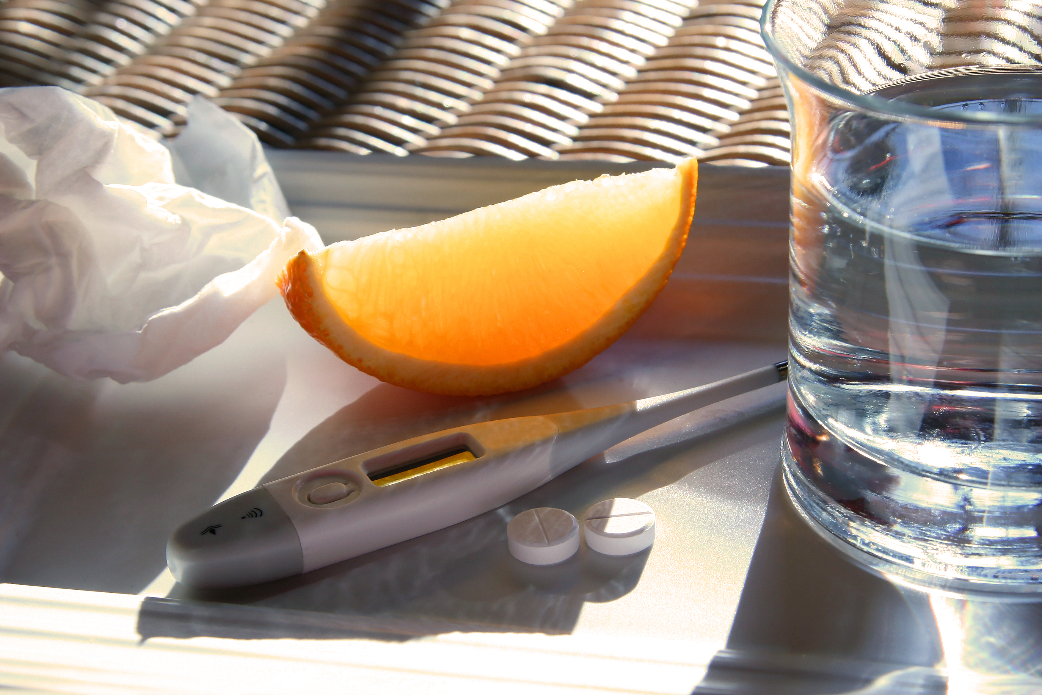 Tissue, orange wedge,water glass, thermometer and cold pills for relief of flu symptoms