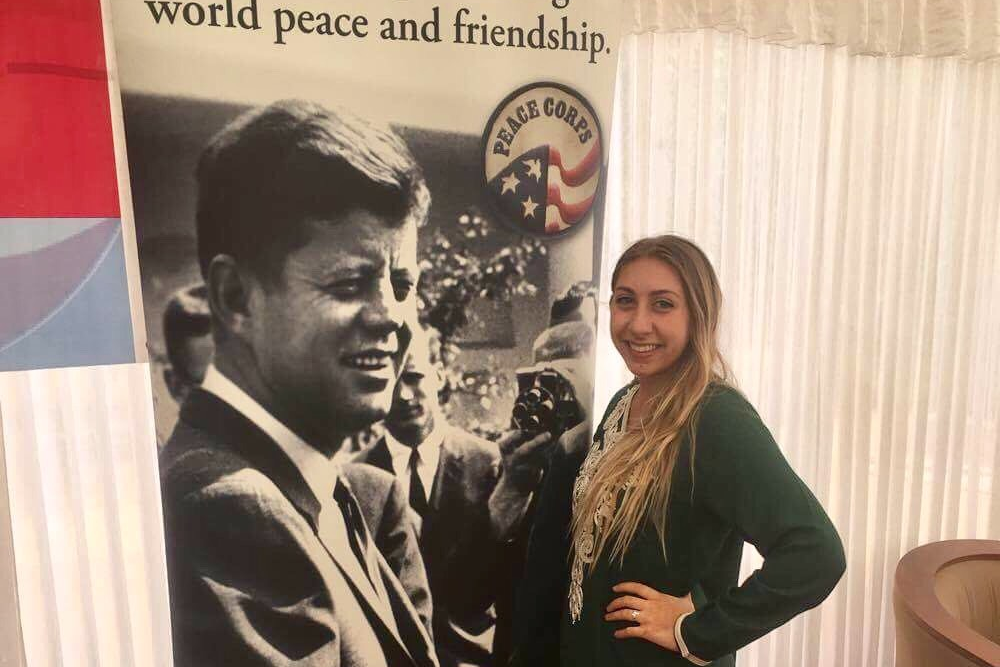 Palecek posing with Peace Corps poster