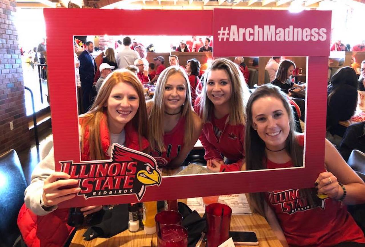 4 female Redbird fans hold an #ArchMadness sign